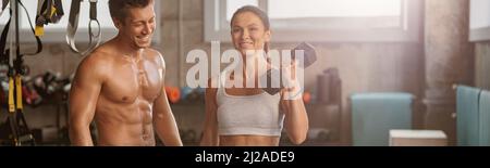 Sporty man in the gym with athletic woman performing sports exercises Stock Photo