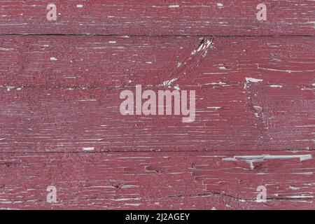 Old wooden worn fence boards weathered texture in peeling red paint dirty obsolete background. Stock Photo