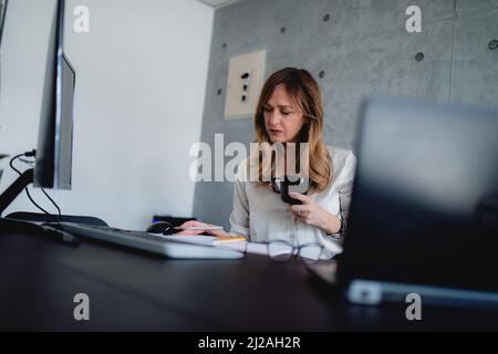 A Caucasian female in a white shirt is making schedules, drinking coffee from a black mug.Manager  gets energy for a meeting in the company. Stock Photo