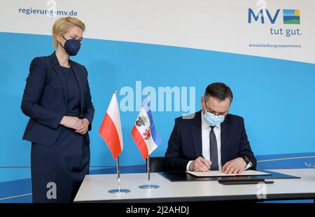 Schwerin, Germany. 31st Mar, 2022. Manuela Schwesig (SPD), Minister President of Mecklenburg-Western Pomerania, stands in the State Chancellery next to Pawel Gronow, Chargé d'Affaires of the Embassy of the Republic of Poland, who signs the Golden Book. Credit: Bernd Wüstneck/dpa-Zentralbild/dpa/Alamy Live News Stock Photo