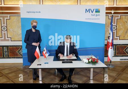 Schwerin, Germany. 31st Mar, 2022. Manuela Schwesig (SPD), Minister President of Mecklenburg-Western Pomerania, stands in the State Chancellery next to Pawel Gronow, Chargé d'Affaires of the Embassy of the Republic of Poland, who signs the Golden Book. Credit: Bernd Wüstneck/dpa-Zentralbild/dpa/Alamy Live News Stock Photo