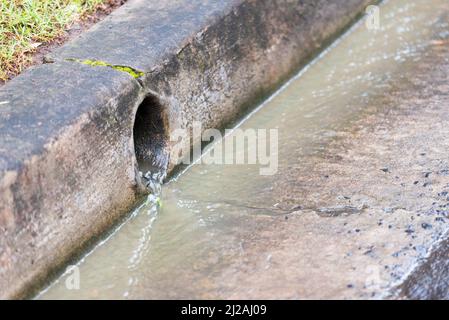 A residential stormwater drain outlet after heavy rain with water running in the gutter and from the drain in Sydney, New South Wales, Australia Stock Photo