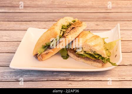 Roast beef sandwich with arugula and sauce with caramelized onions on white plate Stock Photo