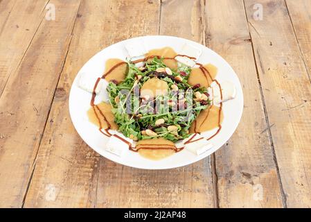 Salad with pumpkin cream, raisins, fried pine nuts, brie cheese, arugula and balsamic vinegar Stock Photo