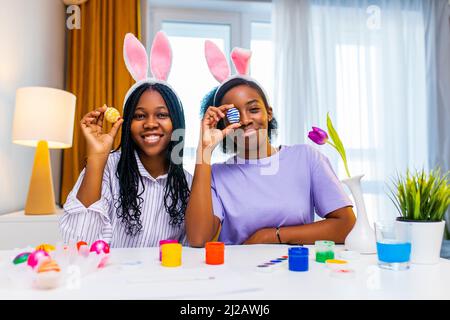 two happy sister with bunny ear painting eggs in apartment preparing to easter Stock Photo