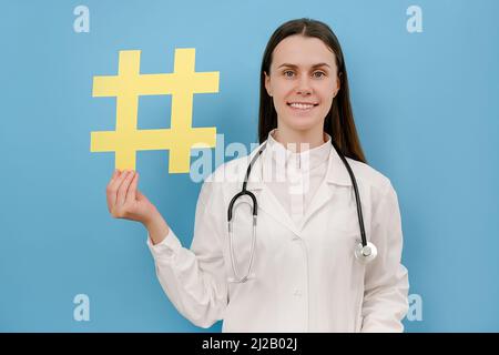 Attractive family doc lady patients consultation beaming friendly smiling reliable virology clinic holds hashtag sign wear white lab coat stethoscope, Stock Photo