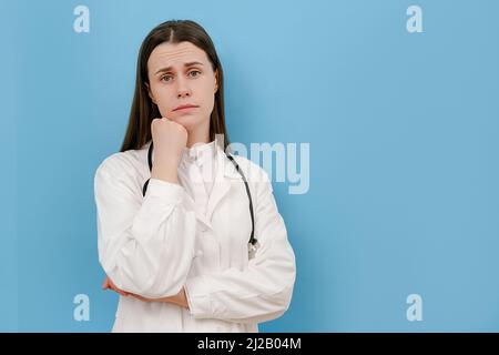 Portrait of upset young woman doctor feeling tension, guilt blaming herself for professional mistake. Depressed worried female therapist thinking of m Stock Photo