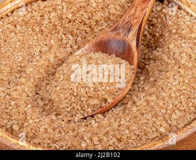 Close-up of granulated cane sugar and a wooden spoon. Cane sugar crystals. Stock Photo