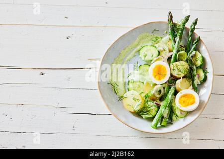 Top view of appetizing fresh asparagus salad with boiled eggs and potatoes served on plate on wooden table Stock Photo