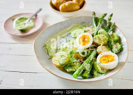 High angle of tasty salad with asparagus and eggs and potatoes served in bowl on wooden table for healthy lunch Stock Photo