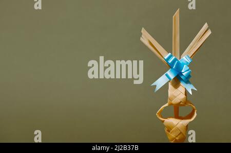 closeup of a traditional Spanish braided palm leaf, typically blessed on Palm Sunday, on a green background with some blank space on the left Stock Photo