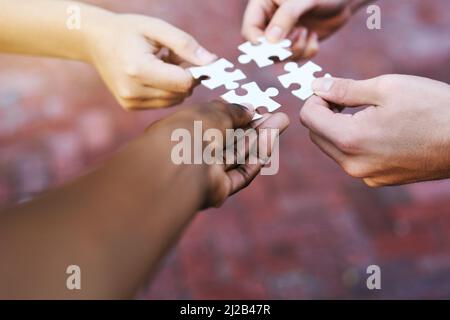 Finding solutions piece by piece. Shot of hands putting puzzle pieces together. Stock Photo