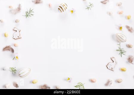 Festive Easter border, frame made of Easter eggs and feathers on a white background. Stylish easter flat lay in white color. Stock Photo