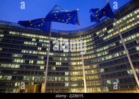 Belgium, Brussels: European Union Flags in front of the Berlaymont building, headquarters of the European Commission, in the evening