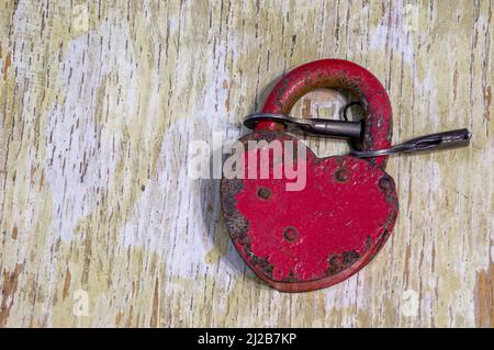 red lock in the shape of a heart with keys on a shabby background Stock Photo