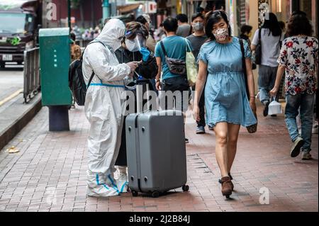Hong Kong. 30th Mar, 2022. A man wearing a personal protective equipment gear (PPE) stops for directions in North Point.Hong Kong has seen a steady decline in daily COVID-19 cases and deaths during the fifth wave of the pandemic. As of March 31, 2022, over 1.15 million cases and more than 7,700 deaths have been recorded. Credit: SOPA Images Limited/Alamy Live News Stock Photo