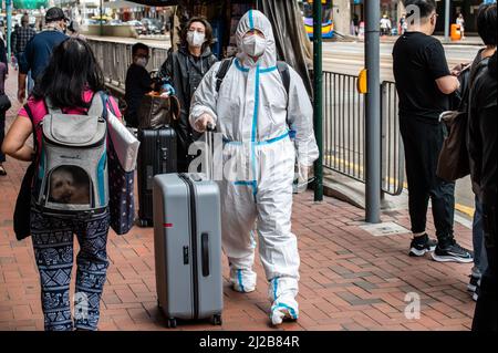 Hong Kong. 30th Mar, 2022. A man wearing a personal protective equipment gear (PPE) strolls down the street in North Point. Hong Kong has seen a steady decline in daily COVID-19 cases and deaths during the fifth wave of the pandemic. As of March 31, 2022, over 1.15 million cases and more than 7,700 deaths have been recorded. Credit: SOPA Images Limited/Alamy Live News Stock Photo