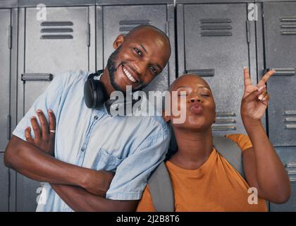 Two young black students pose with silly faces in front of campus lockers Stock Photo
