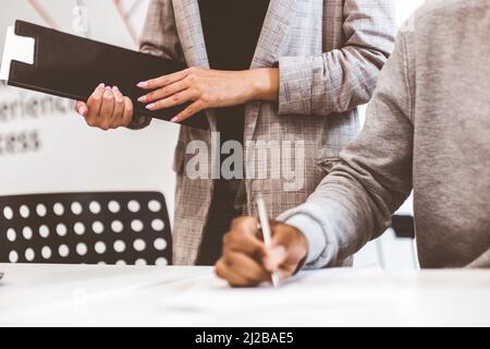 African american man signing contract, black man hand putting signature on official document, biracial clients customers couple make purchase or sign Stock Photo