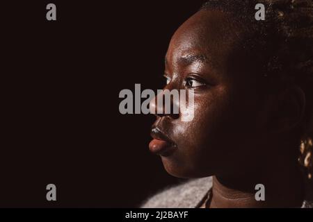 Young woman looking away by black background Stock Photo