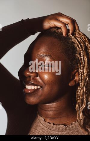 Smiling woman with hand in hair at studio Stock Photo