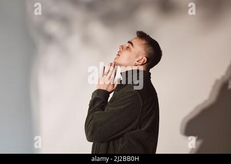 Side view of man with hands clasped by white background in studio Stock Photo