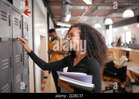 A young mixed race student reaches for her locker. Other students in background Stock Photo