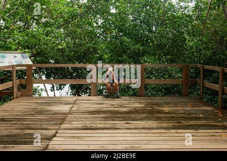 San Andrés, Colombia - December 18 2021: Young White Man Takes a Pictures with his Camera on a Wooden Pathway in a Mangrove Stock Photo