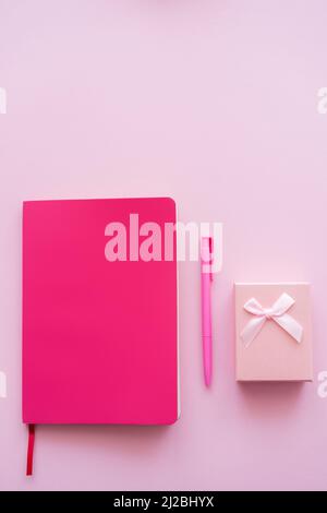 top view of gift box, bright notebook and pen isolated on pink Stock Photo