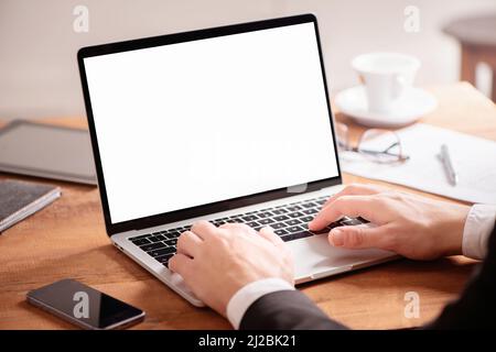 Cropped photo of young businessman using laptop on wooden table. Close up Stock Photo