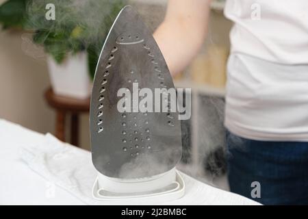 Damaged sole of the iron, brown stains and traces of burning with smoke and steam. Improper behavior during ironing clothes Stock Photo