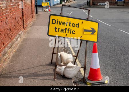 Traffic diversion sign on the side of a road pointing to the right with a red and white cone by the side Stock Photo