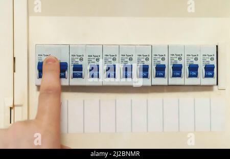 Male hand switching on fuse board. Stock Photo