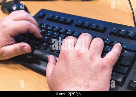 Detail of hands typing on a black keyboard  Stock Photo
