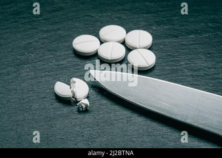 MDMA Pill known as ecstasy  E  or molly, is a psychoactive drug primarily used for recreational purposes. MDMA drugs and knife on black background Stock Photo
