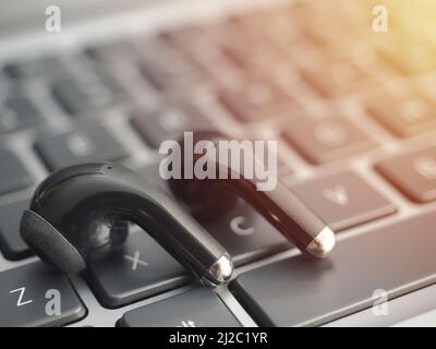 Bluetooth wireless headphones on a laptop keyboard. Watching movies and listening to music on a laptop using bluetooth true wireless headphones Stock Photo