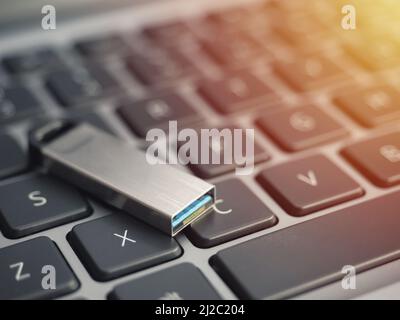 Close up of metal USB 3.0 flash drive connected to laptop on wood desk Stock Photo