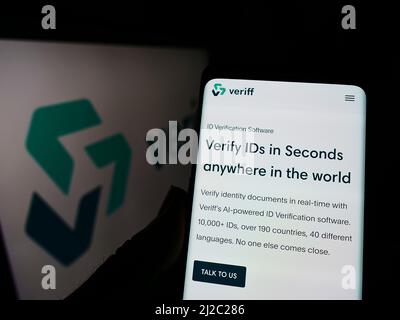Person holding smartphone with webpage of Estonian identity verification company Veriff on screen with logo. Focus on center of phone display. Stock Photo