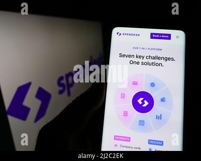 Person holding cellphone with webpage of French fintech company Spendesk SAS on screen in front of logo. Focus on center of phone display. Stock Photo