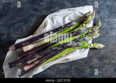 Raw white, purple, green asparagus  on packaging paper. Raw food concept. Stock Photo