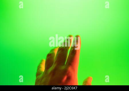 young man's hand trying to touch a green screen. Virtual reality. VR. Stock Photo