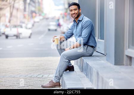 In need of a coffee rush. Shot of a young businessman drinking a cup of coffee in the city. Stock Photo