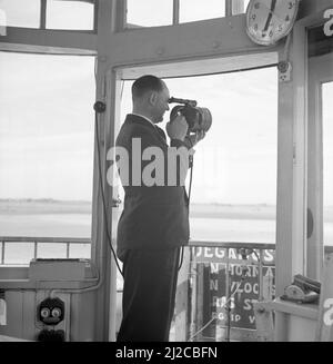 An air traffic controller in the control tower of Schiphol airport while maintaining contact with a signal lamp  ca: 1936 Stock Photo