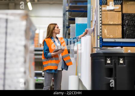 Woman with tablet in factory storehouse checking location of goods Stock Photo