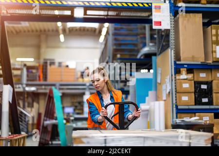 Young worker moving goods on pallet jack at warehouse Stock Photo