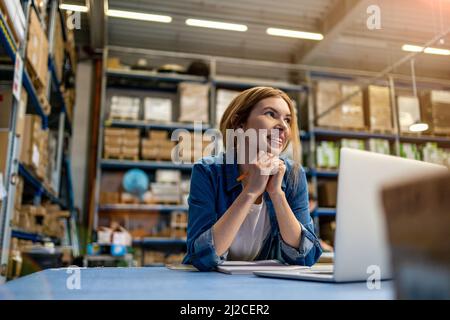 Woman using laptop at warehouse Stock Photo