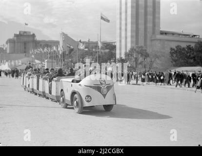 Small train in the exhibition area with a view of the Palais de Chaillot , the front of the German pavilion and a row of flagpoles  ca: 1937 Stock Photo