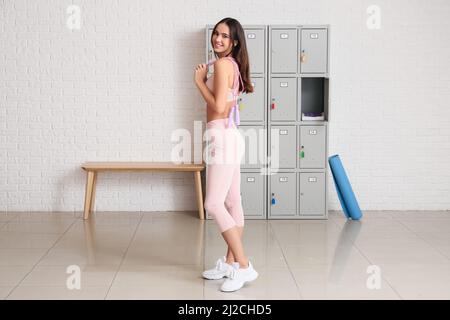 Sporty young woman with jumping rope in locker-room Stock Photo