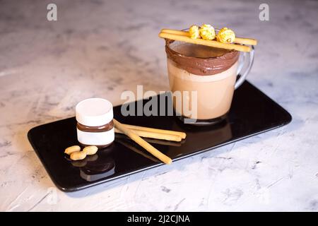 coffee with chocolate paste and cookies on black dishes. Stock Photo