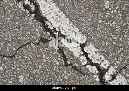 Old damaged cracked asphalt road section with old paint road marking. Texture damage. Deterioration of the road surface. Copy space Stock Photo